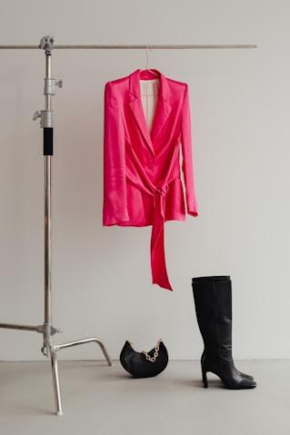 A pink blazer and black boots on a studio rail